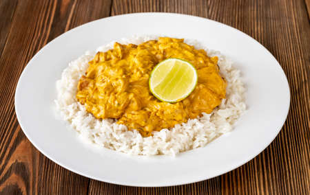 Portion of chicken curry garnished with rice and fresh limeの写真素材