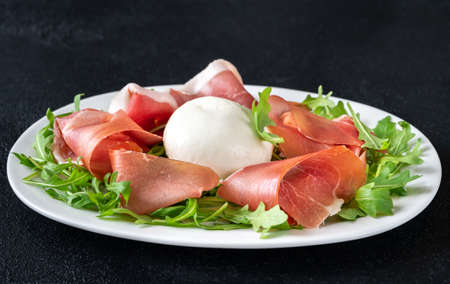 Antipasto with prosciutto , mozzarella and fresh arugula on the serving plateの写真素材