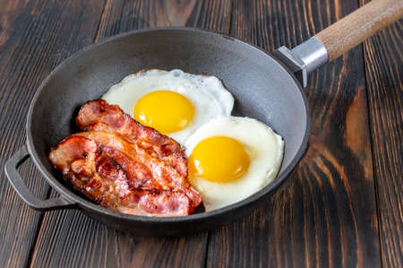 Fried eggs with bacon rashers  on the frying panの写真素材