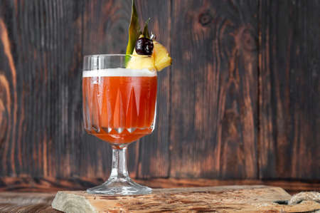 Glass of Club Cocktail garnished with pineapple wedge and maraschino cherryの写真素材
