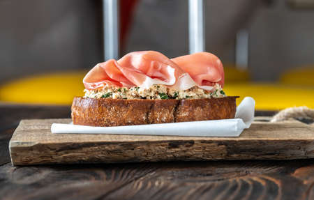 Bruschetta with cream cheese, sun-dried tomatoes and prosciutto on the wooden boardの写真素材