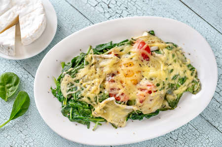 Cheesy baked eggs with spinach and tomatoの写真素材