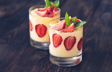 Two glasses of mango custard with fresh strawberries topped with fresh mintの写真素材