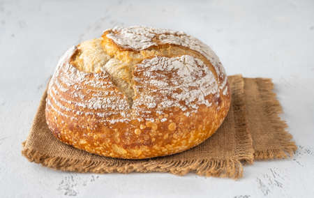 Loaf of fresh sourdough bread on white background