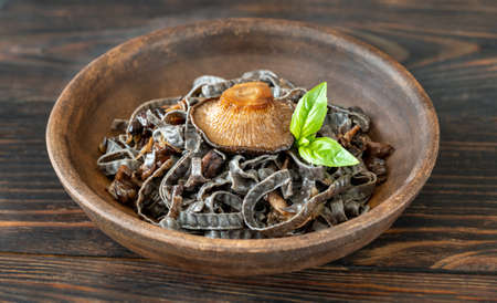 Bowl of cooked black noodles with mushroomsの写真素材