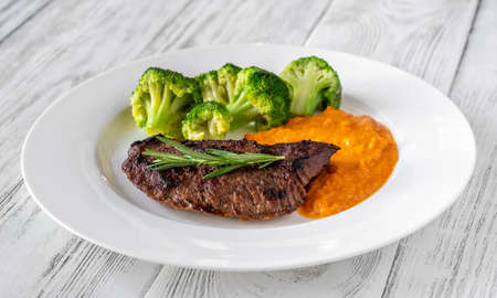 Beef steak with mashed pumpkin on white plateの写真素材