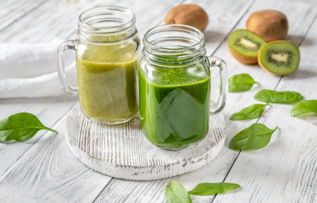 Spinach and kiwi smoothie in mason jars on the wooden boardの写真素材