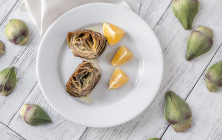 Baked artichoke with lemon on the plateの写真素材