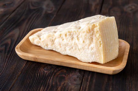 Wedge of parmesan cheese on wooden background