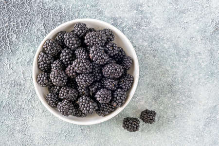 Bowl of fresh blackberry on blue gray background