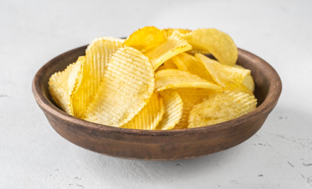 Bowl of waved potato chips on white backgroundの写真素材
