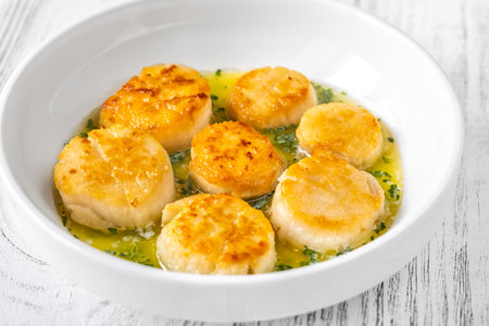 Bowl of fried scallops with melted butter and parsleyの写真素材