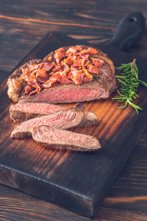 Sliced beef steak with crumbled bacon garnished with rosemaryの写真素材