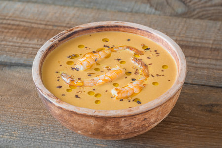 Bowl of bisque soup garnished with shrimps and pepper flakes