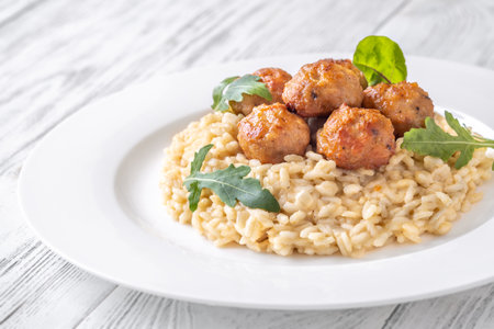 Tender chicken meatball atop creamy risotto, elegant white settingの写真素材