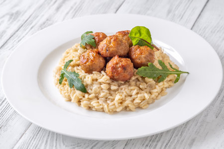 Tender chicken meatball atop creamy risotto, elegant white settingの写真素材