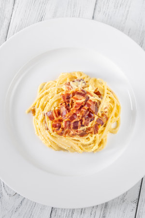 Portion of carbonara pasta garnished with fried guancialeの写真素材