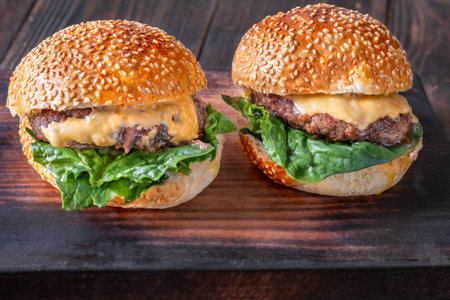Two homemade cheeseburges on the wooden background