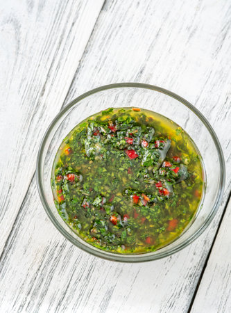 Glass bowl of Chimichurri sauce on the tableの写真素材