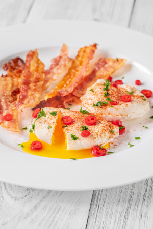 Portion of chili poached eggs with crispy baconの写真素材