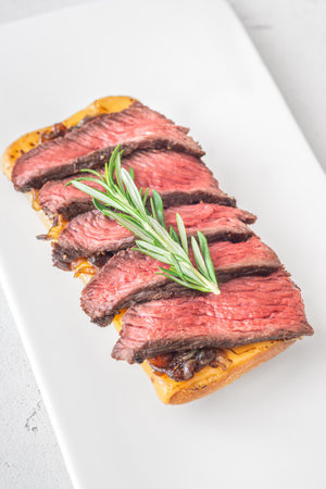 Crispy ciabatta filled with melted cheese, tender steak, sweet onions, and fresh rosemaryの写真素材