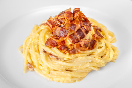 Portion of carbonara pasta garnished with fried guancialeの写真素材
