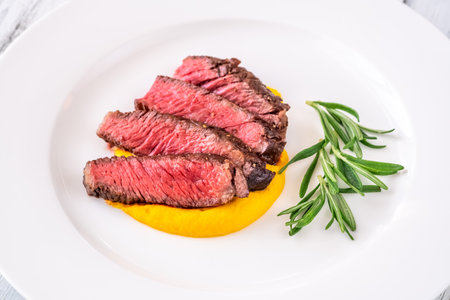 Sliced rib eye steak garnished with carrot and rosemaryの写真素材