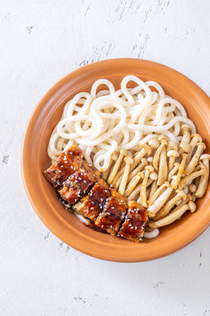 A hearty udon bowl topped with mushrooms and toasted sesame garnishの写真素材