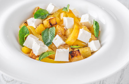 Sweet pineapple, grilled peppers, feta cubes, and mint mingle in vibrant saladの写真素材