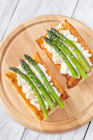 Toasted ciabatta holds creamy cheese and asparagus glistening in golden oilの写真素材