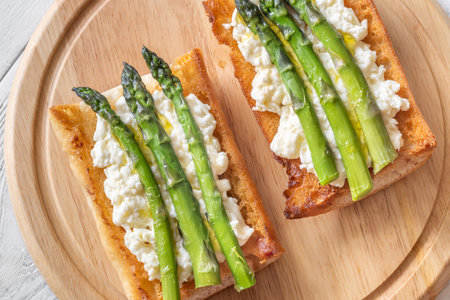Toasted ciabatta holds creamy cheese and asparagus glistening in golden oilの写真素材