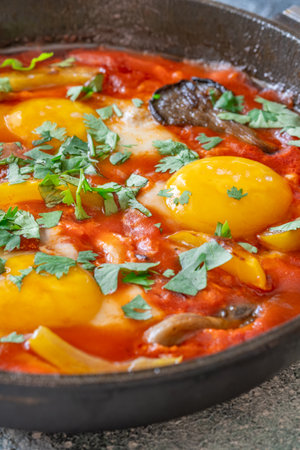 Eggs simmered in spiced tomato base with mushrooms, peppers, and fresh herbsの写真素材
