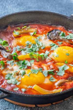 Eggs simmered in spiced tomato base with mushrooms, peppers, and fresh herbsの写真素材
