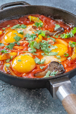 Eggs simmered in spiced tomato base with mushrooms, peppers, and fresh herbsの写真素材