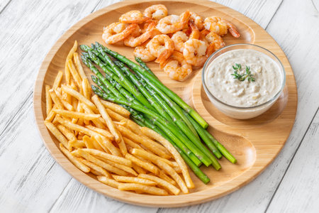 Crispy shrimp and fries balance soft asparagus and creamy sauce with thymeの写真素材