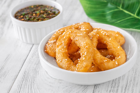 Golden calamari rings topped with sesame seeds, served with spicy Asian sauceの写真素材