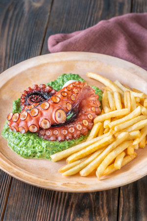 Roasted octopus tentacles served with creamy spinach and golden fries, rustic plating styleの写真素材