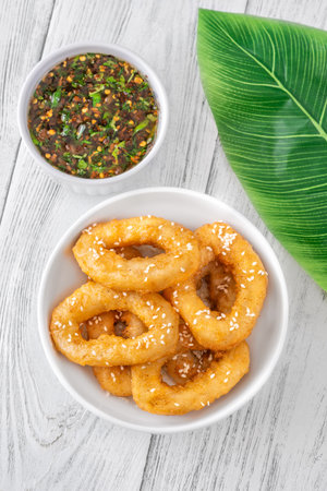 Golden calamari rings topped with sesame seeds, served with spicy Asian sauceの写真素材