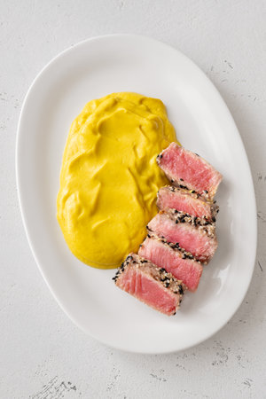 Crisp sesame tuna rests beside smooth cauliflower curry, balanced and visually refinedの写真素材