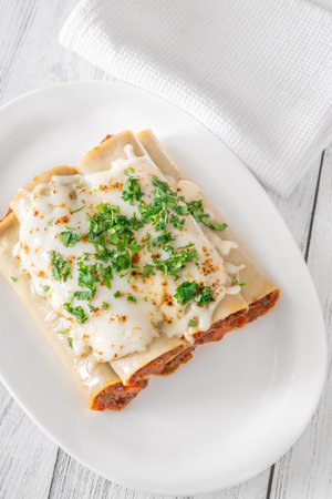 Delicate cannelloni pasta, generously filled with rich bolognese sauce, baked under a blanket of melted mozzarellaの写真素材