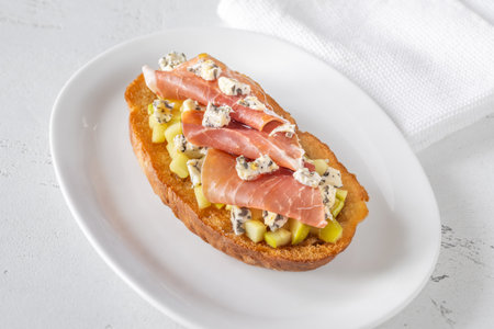 Warm sandwich stacked with creamy cheese, salty ham, sweet apple, and honeyの写真素材