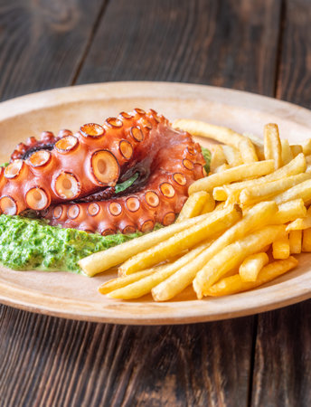 Roasted octopus tentacles served with creamy spinach and golden fries, rustic plating styleの写真素材