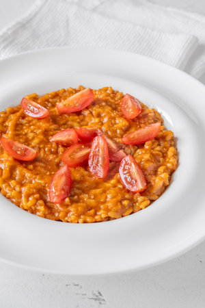 Tomato risotto plated simply with cherry tomato garnish and vibrant warmthの写真素材