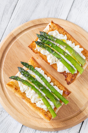 Toasted ciabatta holds creamy cheese and asparagus glistening in golden oilの写真素材
