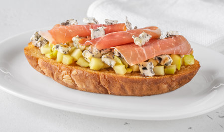 Warm sandwich stacked with creamy cheese, salty ham, sweet apple, and honeyの写真素材