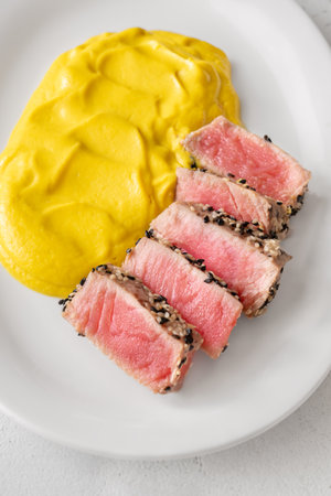 Crisp sesame tuna rests beside smooth cauliflower curry, balanced and visually refinedの写真素材