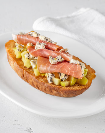 Warm sandwich stacked with creamy cheese, salty ham, sweet apple, and honeyの写真素材