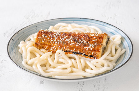 Thick udon noodles topped with glazed eel, richly coated in savory unagi sauceの写真素材
