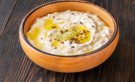 Roasted eggplant dip topped with chili flakes and oil in rustic settingの写真素材