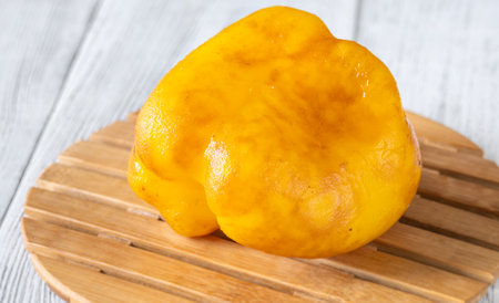 Charred yellow pepper glistens with grill marks, resting simply on aged woodの写真素材